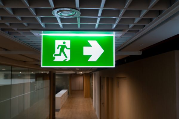 Green fire escape sign hang on the ceiling in the office.